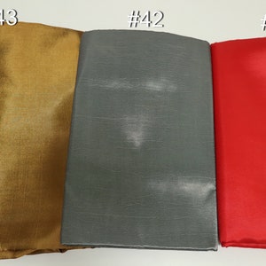 May include: Three fabric swatches in gold, gray, and red. The gold swatch is labeled #43, the gray swatch is labeled #42, and the red swatch is labeled #14. The fabrics have a smooth texture and appear to be folded.