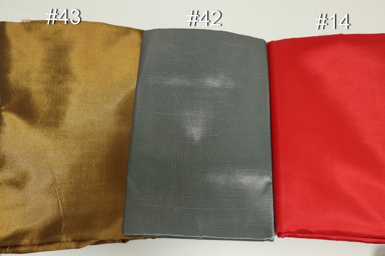 May include: Three fabric swatches in gold, gray, and red. The gold swatch is labeled #43, the gray swatch is labeled #42, and the red swatch is labeled #14. The fabrics have a smooth texture and appear to be folded.