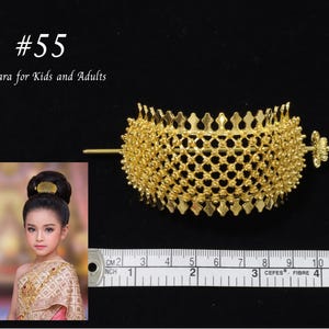 May include: A gold-colored hair accessory featuring a curved, lattice-patterned metal piece with a pointed top edge and a horizontal pin. The text #55 Tiara for Kids and Adults is visible. A measuring tape shows the piece is 3.5 inches wide.