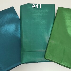May include: Three folded fabric swatches in shades of green and teal. The swatches are labeled with white numbers: #24, #41, and #5. The fabric has a shiny, textured appearance.