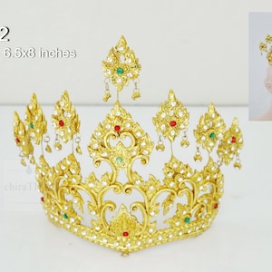 May include: A gold crown with red and green gemstones, and white beads. The crown is 6.5 x 8 inches.