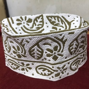 Puede incluir: Una gorra blanca de algodón con un patrón floral bordado en verde.