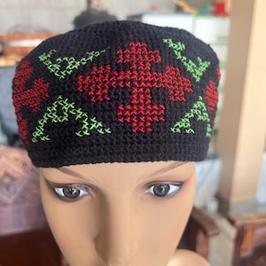 May include: Black crocheted hat with red and green embroidered floral designs.