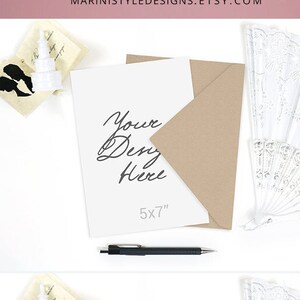 May include: A mockup featuring two 5x7 inch cards with white and craft envelopes. The cards have the text "Your Design Here" and "5x7". Decorative white fans and a pen are also included. The text "WHITE & CRAFT envelope design INCLUDED" is at the bottom.