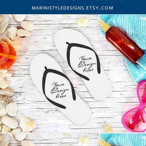 May include: Flip-flop mockup with white and blue sandals, each with the text "Your Design Here." The image includes sunglasses, a drink, seashells, and sunscreen on a white wooden surface. The text "FLIP FLOPS MOCKUP" is at the top.