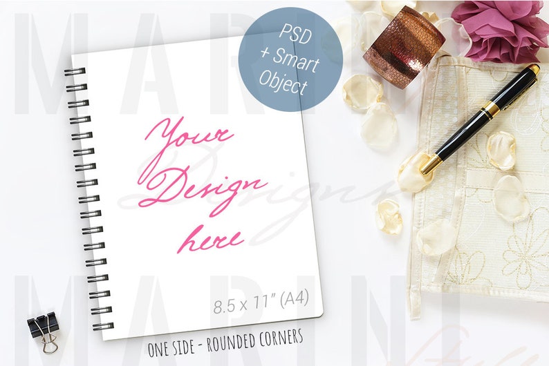 K&ouml;nnte beinhalten: Wei&szlig;es Spiralnotizbuch mit dem rosa Schriftzug "Your Design here". Das Notizbuch ist 21,6 x 27,9 cm (A4) gro&szlig; und hat abgerundete Ecken. Ein schwarz-goldener Stift, eine dekorative Manschette und Bl&uuml;tenbl&auml;tter sind ebenfalls vorhanden.