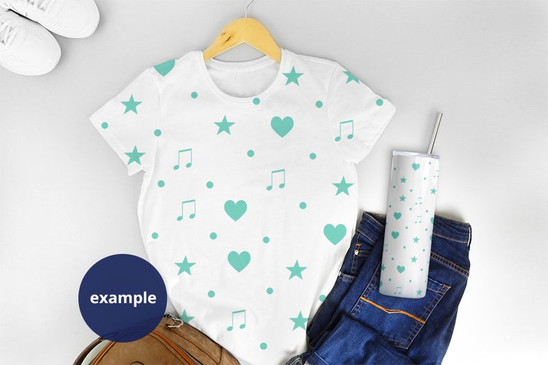 May include: White t-shirt with a teal blue pattern of stars, hearts, and music notes. The t-shirt is on a hanger and there is a teal blue patterned tumbler next to it.