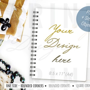 May include: A white spiral-bound notebook with the text "Your Design here" in gold script. The notebook is 21.6 x 27.9 cm (A4) and has rounded corners. A black and gold pen and other accessories are arranged around the notebook.