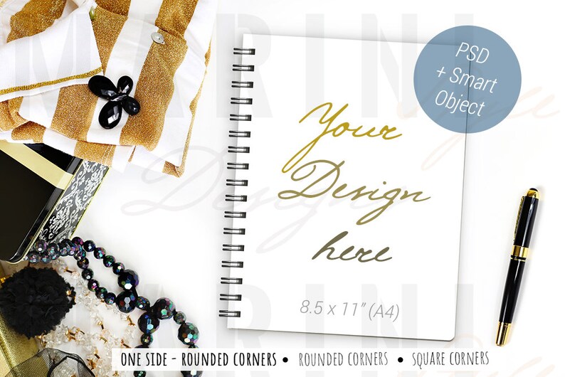 May include: A white spiral-bound notebook with the text "Your Design here" in gold script. The notebook is 21.6 x 27.9 cm (A4) and has rounded corners. A black and gold pen and other accessories are arranged around the notebook.