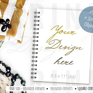 May include: A white spiral-bound notebook with the text "Your Design here" in gold script. The notebook is 21.6 x 27.9 cm (A4) and has rounded corners. A black and gold pen rests beside it, with other accessories.