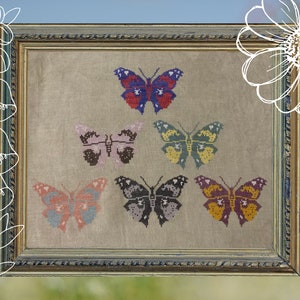 May include: A framed cross-stitch embroidery featuring six colorful butterflies with intricate details. The butterflies are arranged in a symmetrical pattern on a beige linen background.
