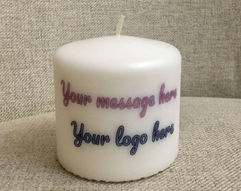 Könnte beinhalten: Weiße Kerze in Säulenform mit dem Text "Your message here" in Rosa und "Your logo here" in Blau.