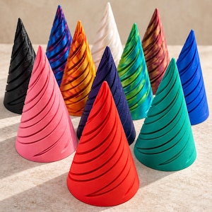May include: A collection of twelve conical ring holders, each featuring a distinct spiral texture. The set includes individual cones in solid colours of black, pink, red, dark blue, teal, green, orange, and white, alongside marbled patterns.