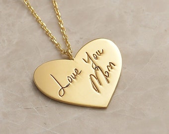 Puede incluir: Collar de corazón de oro con una inscripción manuscrita que dice "Love you Mom".