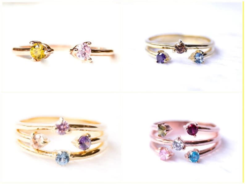 May include: Four gold rings with different colored gemstones. The rings are stacked on top of each other, with the top ring having a single gemstone and the bottom ring having three gemstones.