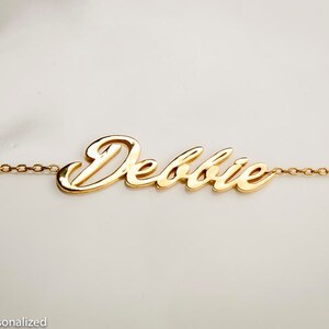 K&ouml;nnte beinhalten: Goldkette mit dem Namen "Debbie" in einer kursiv geschriebenen Schrift.