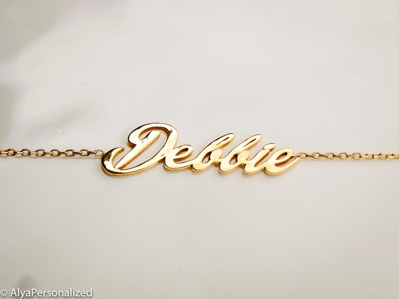 K&ouml;nnte beinhalten: Goldkette mit dem Namen "Debbie" in einer kursiv geschriebenen Schrift.