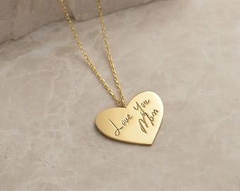 Puede incluir: Collar de corazón de oro con un mensaje escrito a mano que dice "Love you Mom".