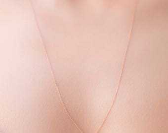 Può includere: Una delicata collana a catena d'oro con un piccolo ciondolo di pietra nera.