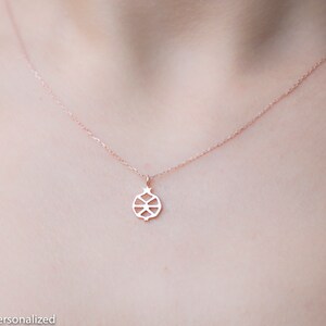 May include: A delicate rose gold necklace with a small, intricate pomegranate pendant.