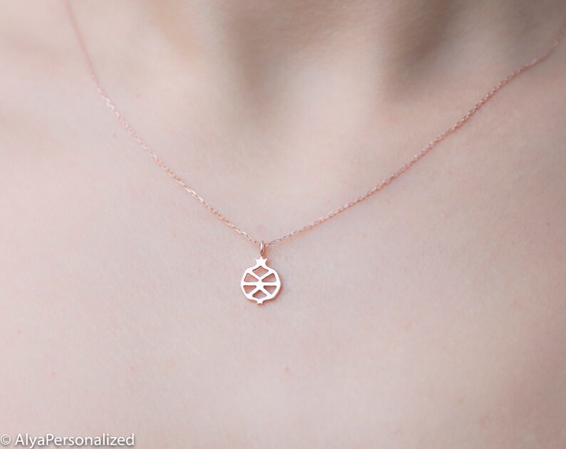 May include: A delicate rose gold necklace with a small, intricate pomegranate pendant.
