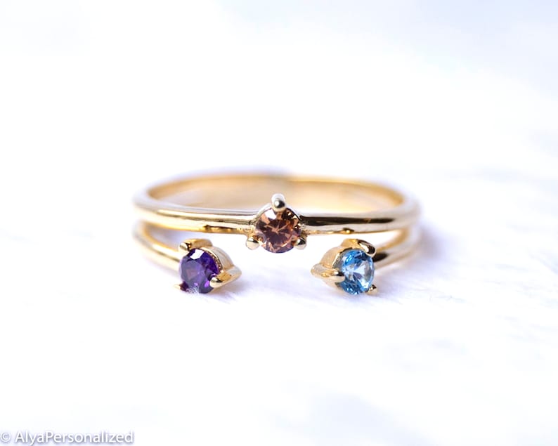 May include: A gold ring with three small gemstones. The gemstones are purple, brown, and blue.