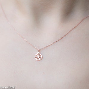 May include: A delicate rose gold necklace with a geometric pendant in the shape of a pomegranate. The pendant is made of a thin metal and has a detailed design.