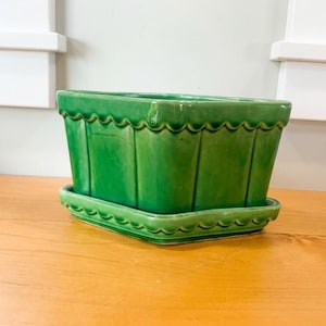 May include: A rectangular green ceramic planter with a glossy finish, featuring a scalloped top edge and vertical ribbed detailing on the sides. The planter sits securely inside a matching green rectangular saucer with a scalloped edge.