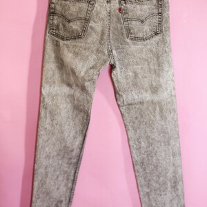 May include: A pair of grey acid wash jeans with a red Levi's tab on the back pocket.