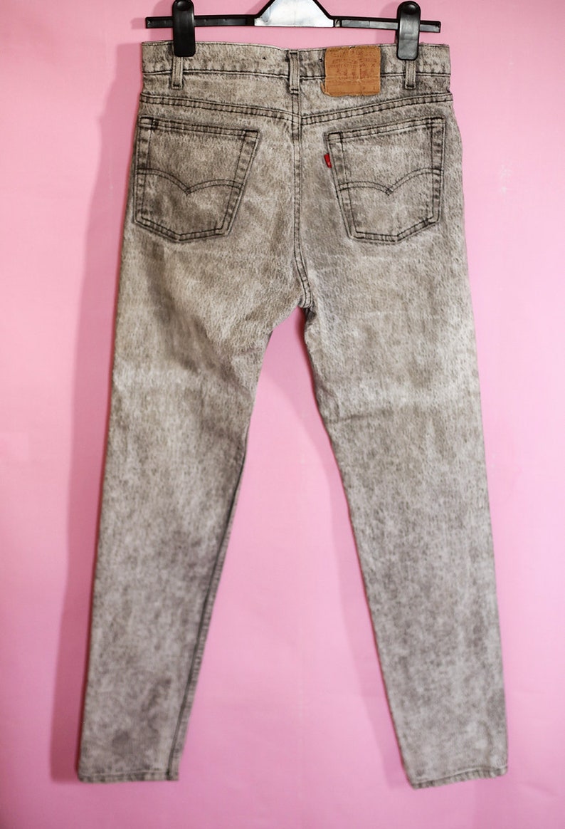 May include: A pair of grey acid wash jeans with a red Levi's tab on the back pocket.