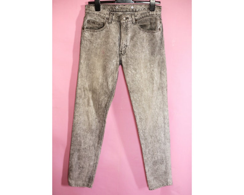 May include: Gray acid wash denim jeans with a straight leg fit.