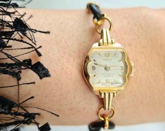 Raro orologio da polso da donna vintage anni '50 placcato in oro con cassa quadrata arrotondata e decorata con 15 gioielli e cinturino in pelle nera sottile e delicato di ORIS
