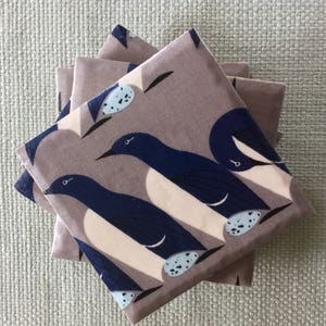 May include: Set of four brown coasters with a blue and white bird design. The birds are stylized and have a simple, modern look. The coasters are made of a durable material and are perfect for protecting your furniture from spills and scratches.