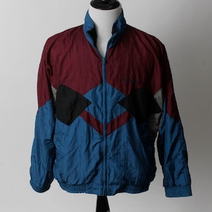 May include: A blue, burgundy, and black windbreaker jacket with a zipper closure. The jacket has a geometric pattern.