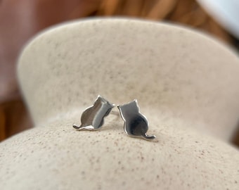 May include: A pair of silver cat silhouette stud earrings. The earrings are small and delicate, and they would make a great gift for any cat lover.