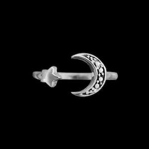 May include: A silver ring with a crescent moon design and a small star on the side.