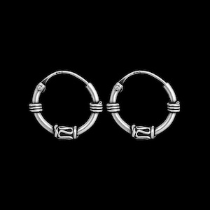 May include: A pair of silver hoop earrings with a decorative design. The hoops are small and have a simple, elegant look.