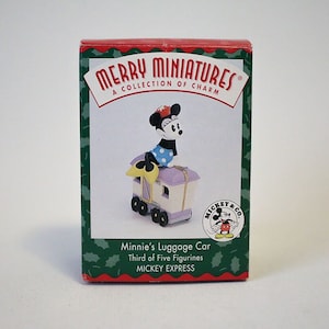 May include: A red box with a green border and a white background. The box features a cartoon image of Minnie Mouse in a blue and white polka dot dress, riding a purple luggage car. The text on the box reads "MERRY MINIATURES", "A COLLECTION OF CHARM", "Minnie's Luggage Car", "Third of Five Figurines", and "MICKEY EXPRESS".