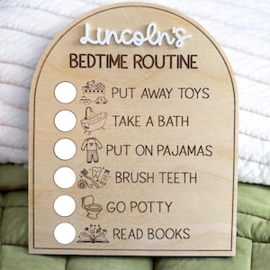 Puede incluir: Tabla de rutina para la hora de dormir de madera con el nombre "Lincoln's" en escritura blanca. La tabla enumera las tareas de la hora de dormir con iconos correspondientes: guardar los juguetes, tomar un baño, ponerse el pijama, cepillarse los dientes, ir al baño y leer libros.