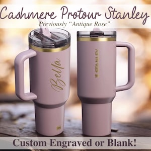 May include: Two light purple Stanley tumblers with gold trim and handles. One is engraved with "Bella." The image text reads "Cashmere Protour Stanley" and "Custom Engraved or Blank!"