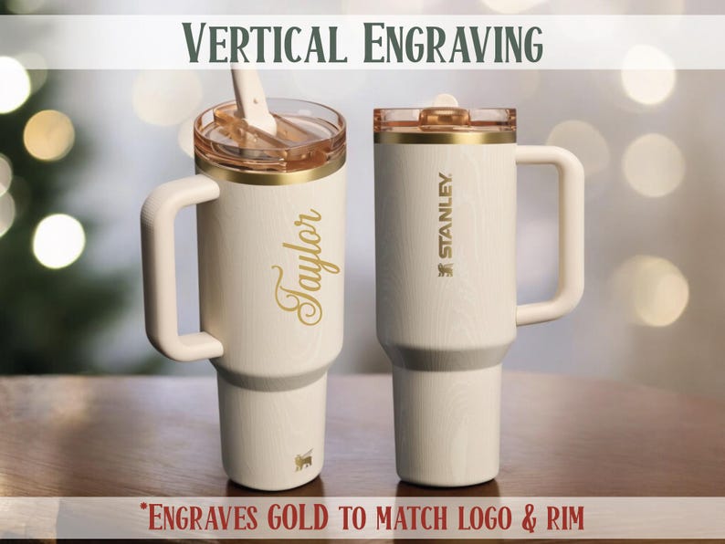 May include: Two white insulated tumblers with gold accents and handles. One tumbler has the name "Taylor" in gold script, the other has the "Stanley" logo. The text "VERTICAL ENGRAVING" and "*ENGRAVES GOLD TO MATCH LOGO & RIM" are also visible.