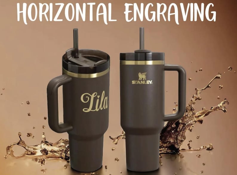 Puede incluir: Dos vasos Stanley marrones con asas y detalles dorados. Uno tiene el nombre "Lila" en escritura dorada. El otro presenta el logotipo de Stanley. El texto "HORIZONTAL ENGRAVING" est&aacute; en la parte superior.