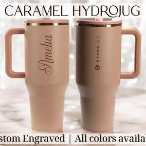 May include: Two caramel-coloured Hydrojugs with handles and lids. One is engraved with the name "Amelia", the other has "HYDROJUG" printed on it. The text "CARAMEL HYDROJUG", "Custom Engraved", and "All colours available" are also visible.