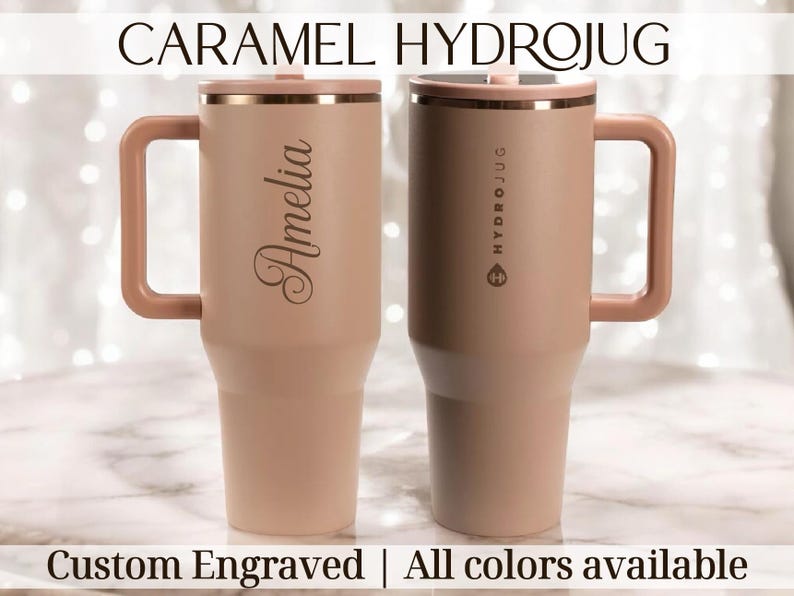 May include: Two caramel-coloured Hydrojugs with handles and lids. One is engraved with the name "Amelia", the other has "HYDROJUG" printed on it. The text "CARAMEL HYDROJUG", "Custom Engraved", and "All colours available" are also visible.