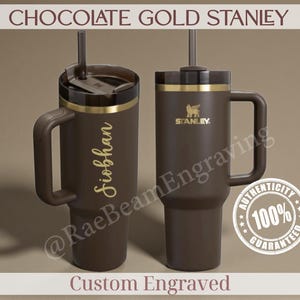 Puede incluir: Dos vasos Stanley marr&oacute;n chocolate con detalles dorados y asas. Uno est&aacute; grabado con un nombre en oro. El otro presenta el logotipo de Stanley. El texto "CHOCOLATE GOLD STANLEY" est&aacute; en la parte superior.