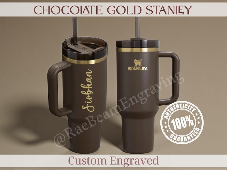 Puede incluir: Dos vasos Stanley marr&oacute;n chocolate con detalles dorados y asas. Uno est&aacute; grabado con un nombre en oro. El otro presenta el logotipo de Stanley. El texto "CHOCOLATE GOLD STANLEY" est&aacute; en la parte superior.