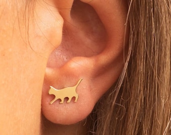 May include: Gold-colored cat-shaped stud earrings. One earring is shown on an ear, and two other earrings are displayed separately. The image also shows the screw back and push back closure styles.