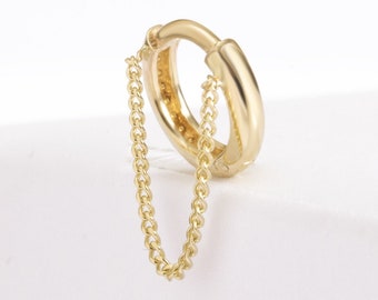 May include: A gold hoop earring with a delicate gold chain attached. The chain hangs down from the hoop.