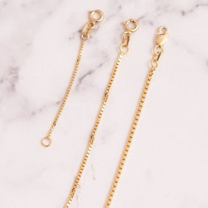May include: Three gold chain extenders of different lengths. The extenders are made of a delicate box chain and have lobster claw clasps.