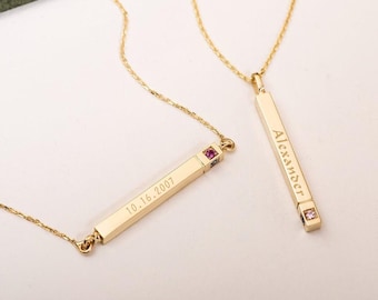 May include: Two gold bar necklaces with birthstone accents. One necklace has the name "Alexander" engraved on the bar and the other has the date "10.16.2007" engraved on the bar.